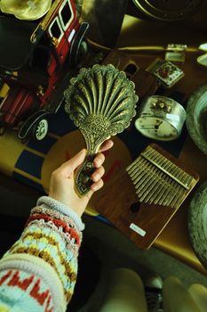 Overhead shot of a vintage ornate hand mirror being held, surrounded by various antique items.