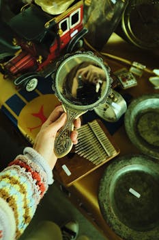 Person photographing their reflection in a vintage hand mirror at an antique store.