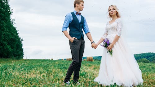 Newlyweds Holding Hands and Posing on Field
