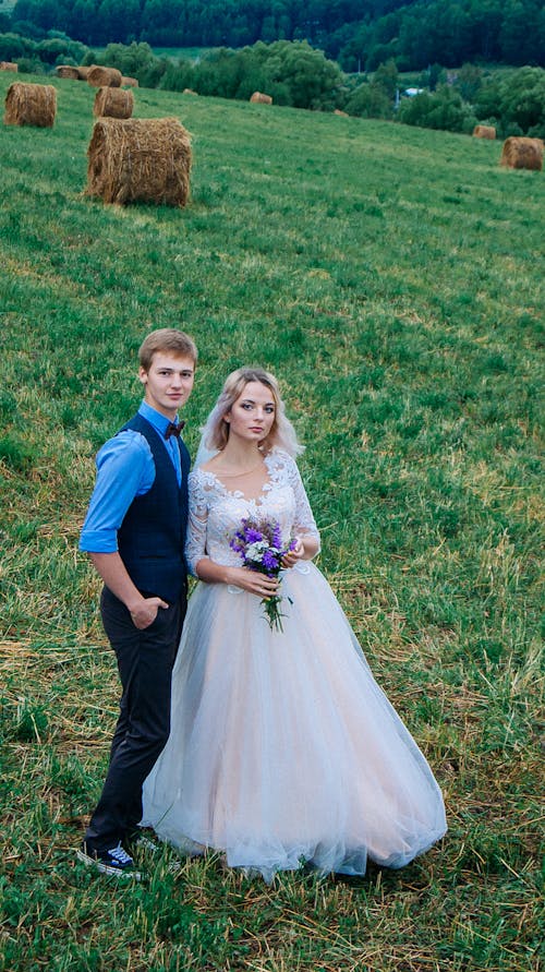 Newlyweds Posing on Field with Hay Bales