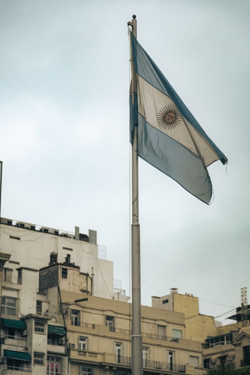 Free Argentinian flag waving against Buenos Aires cityscape, showcasing urban architecture. Stock Photo