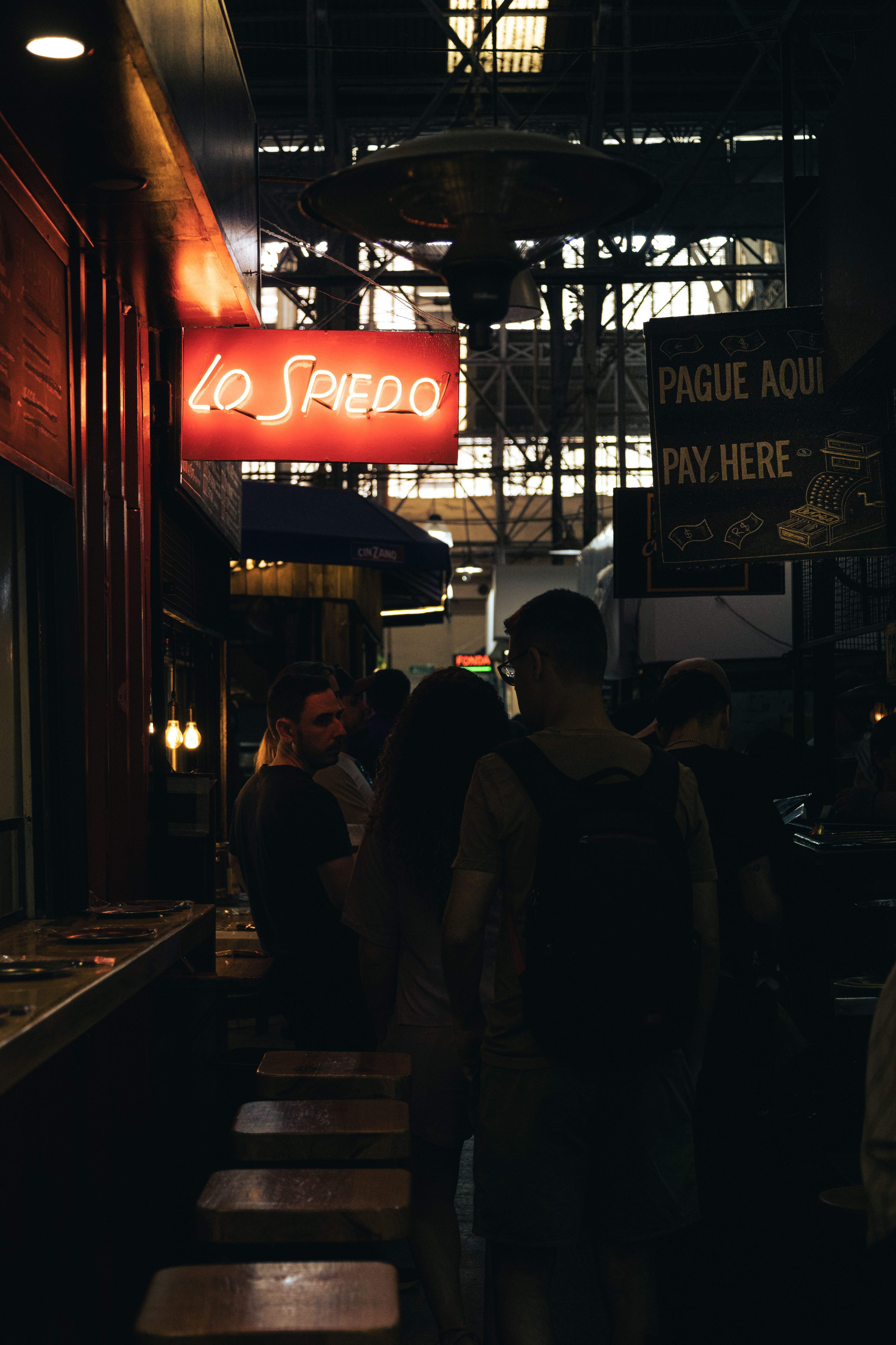 Uma cena vibrante noturna dentro de um bar em Buenos Aires com letreiros de neon e clientes.