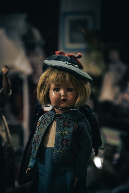 Free Classic vintage doll with blonde hair, hat, and embroidered clothing in a moody setting. Stock Photo