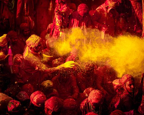 Free Colorful Holi festivities in Vrindavan with people joyfully throwing vibrant powders. Stock Photo