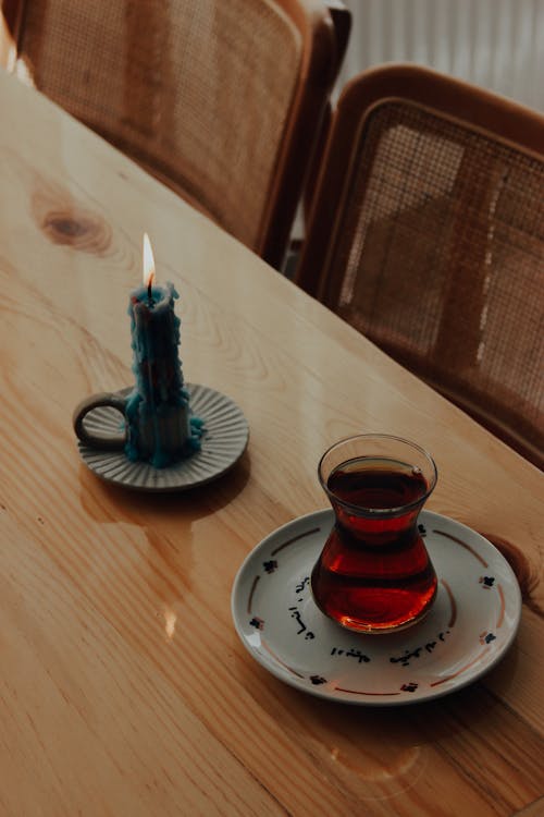 Tea in a Glass and a Lit Candlestick on a Table 