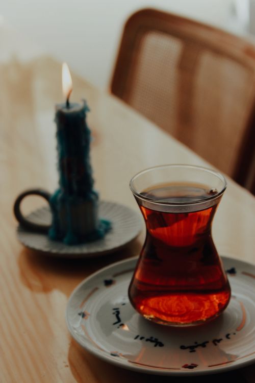 Free Warm tea beside a melting candle on a wooden table, creating a cozy ambiance. Stock Photo