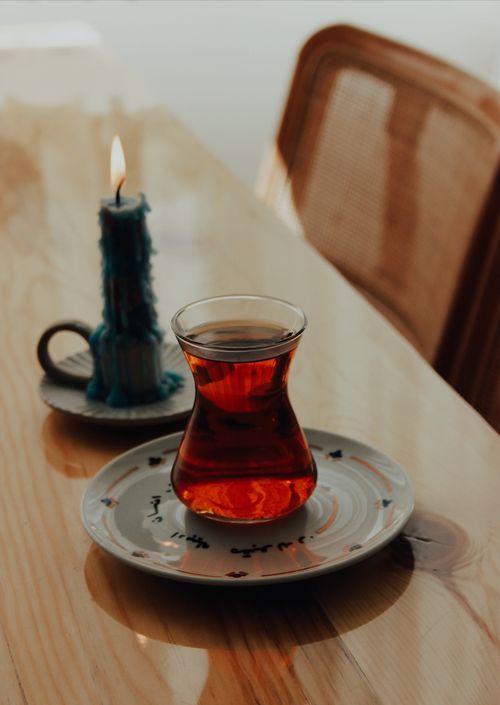 Free A calming setup featuring Turkish tea in a glass with a burning candle on a wooden table. Stock Photo