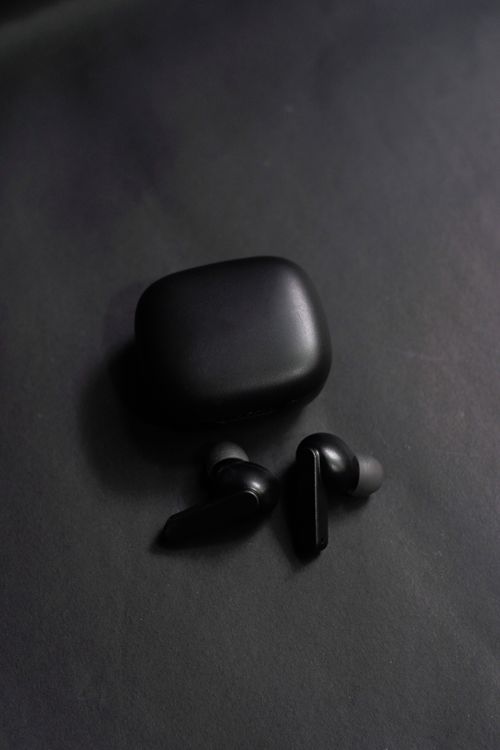 Free Black wireless earphones and case on a dark background. Sleek and minimalist design for modern technology use. Stock Photo