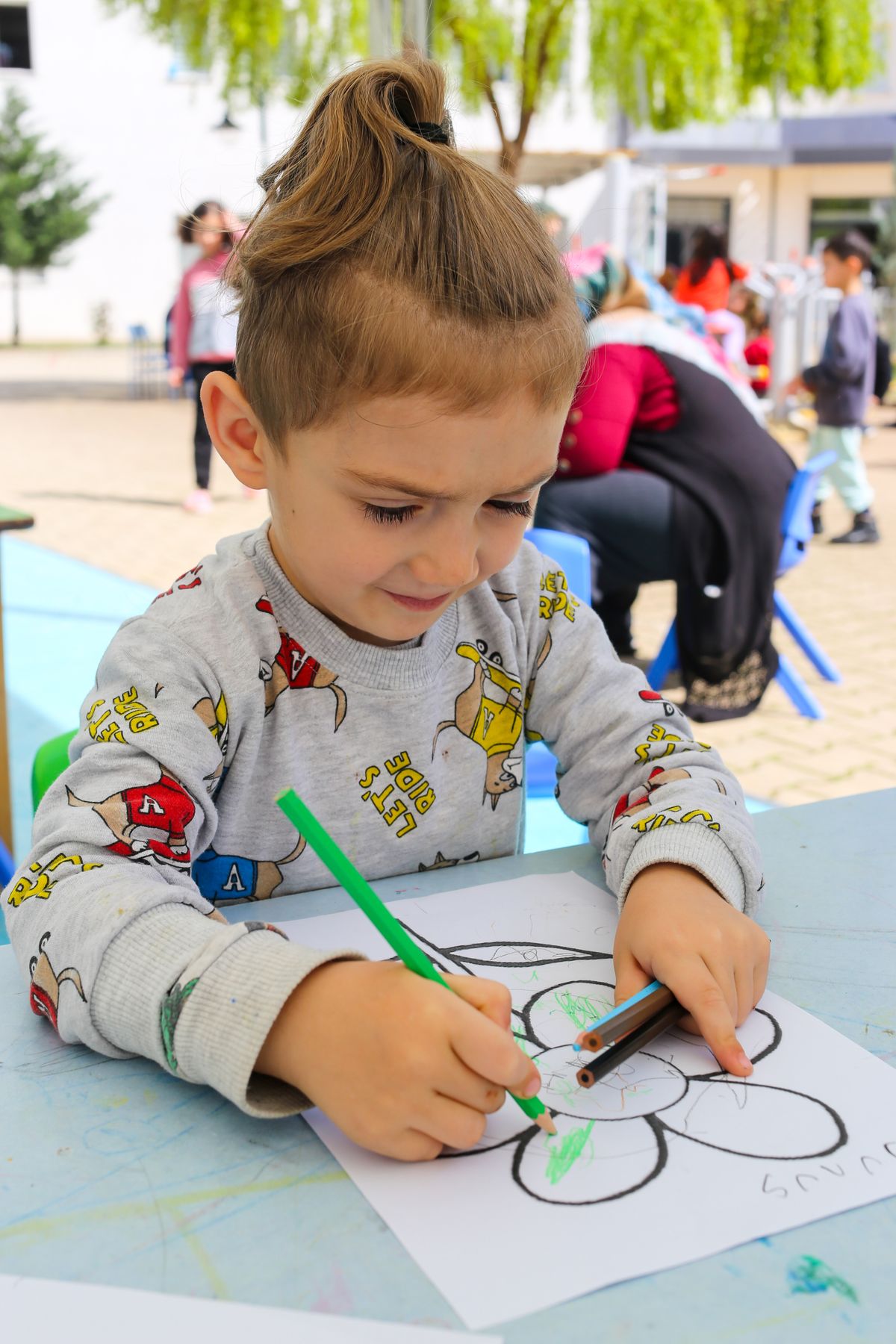 Young child drawing a butterfly at an outdoor festival art table