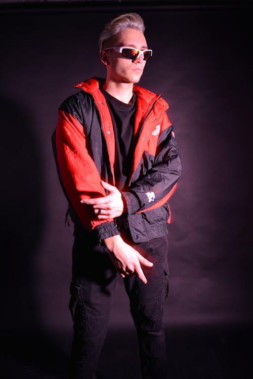 Blonde Man with Sunglasses in Red and Black Jacket Posing in Studio