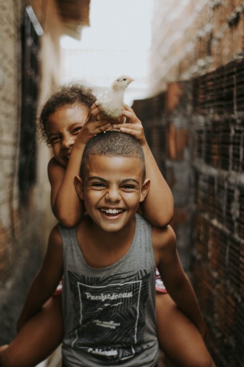 Free Smiling children enjoying a playful moment in an alley, highlighting joy and innocence. Stock Photo