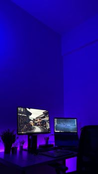 Elegant gaming desk setup with dual screens and blue ambient lighting for gaming enthusiasts.