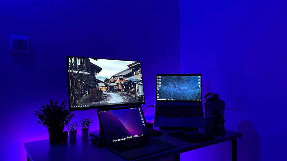 Sleek gaming desk setup with multiple screens and blue neon lighting, perfect for tech enthusiasts.