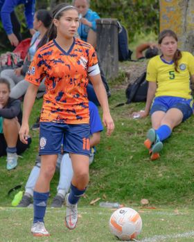 A young woman soccer player stands on the field during a match, ready to play.
