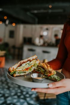 A close-up of a vegetarian sandwich served in a cozy café setting.