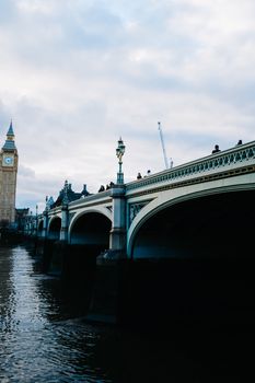 Dramatic view of Westminster Bridge with Big Ben in the backdrop under an overcast sky.