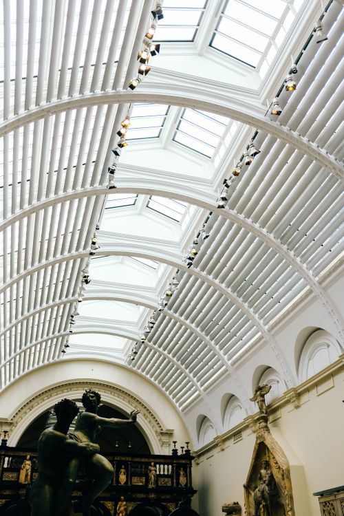 Free Arched skylight ceiling with classical sculptures in a museum, featuring bright natural lighting. Stock Photo