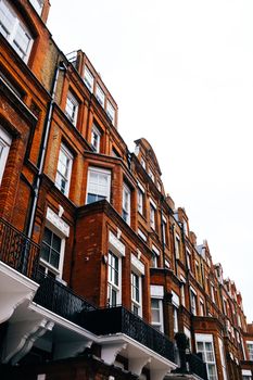Low angle view of classic brick terrace houses against a bright sky in urban area.