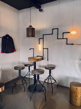 Industrial interior design with pipe lighting and bar stools in a modern setting.