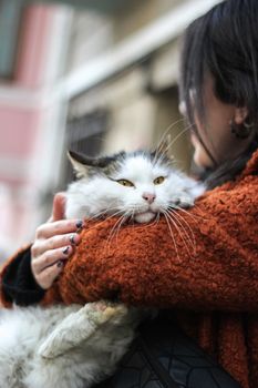 A woman warmly embraces her fluffy cat on a street in İstanbul, Türkiye.