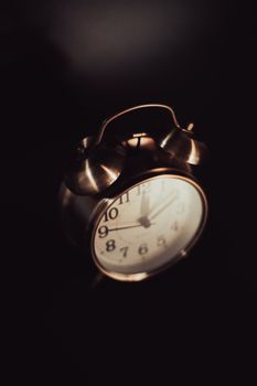 Close-up of a vintage brass alarm clock with a classic dial in a dimly lit setting, highlighting retro charm.