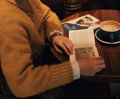 Free Woman Sitting at the Table in a Cafe and Reading a Book  Stock Photo