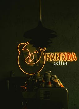 Warm cozy cafe setting with a bright neon 'Pankoa coffee' sign and modern decor.