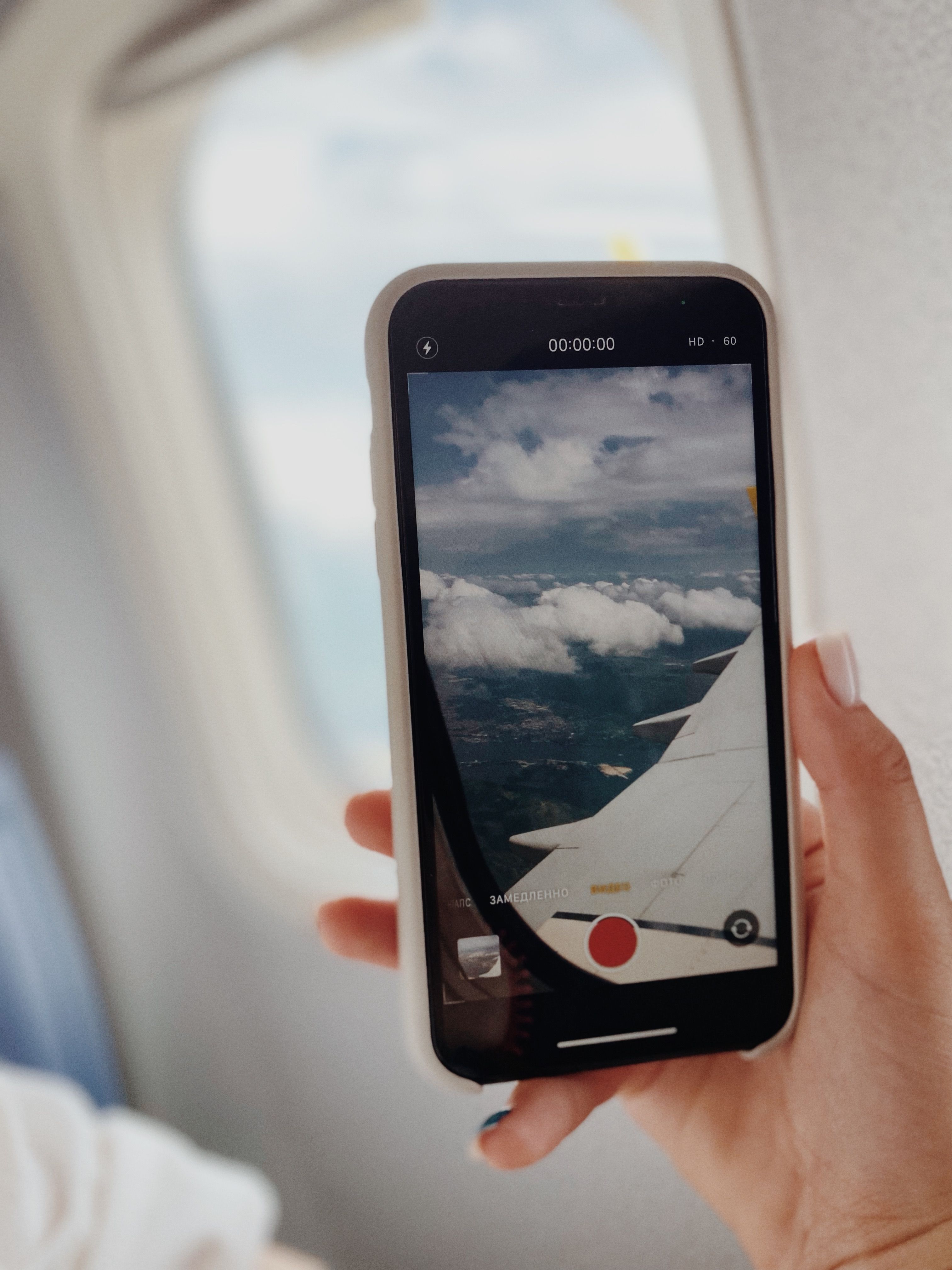 Photo of an airplane wing viewed through a smartphone screen inside a plane.