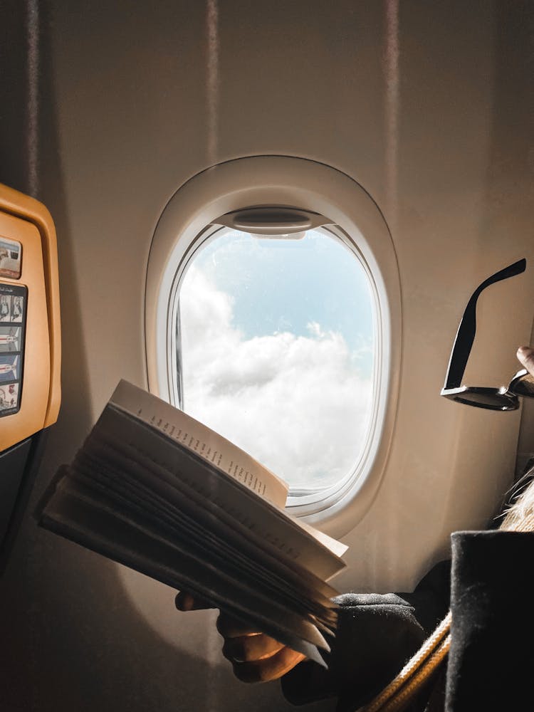 Person Reading Book In Airplane