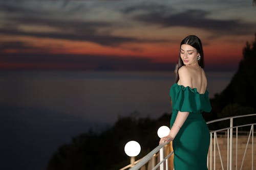 Woman in Green Strapless Evening Dress on Balcony at Sunset