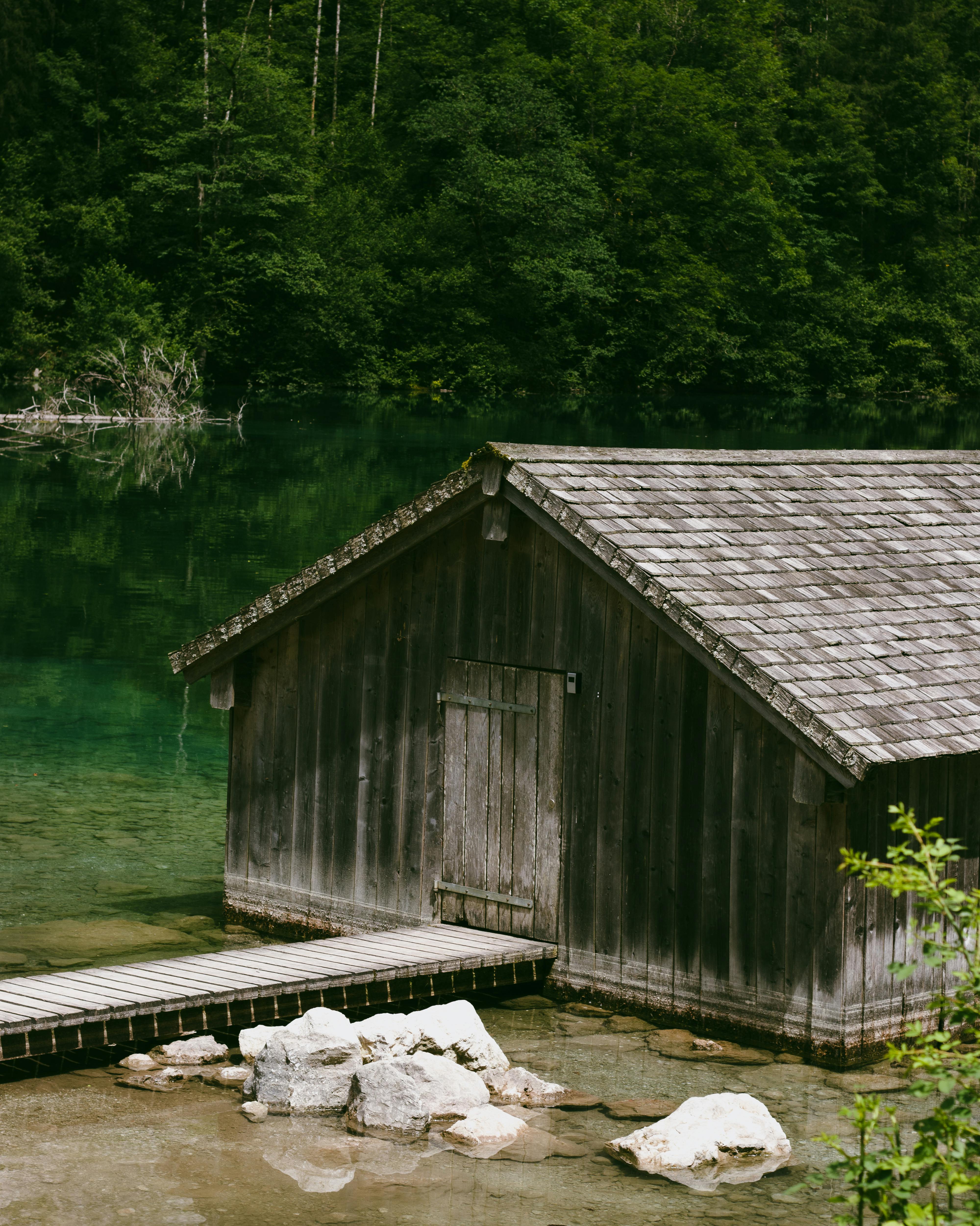 A serene wooden cabin beside a lush forest and emerald lake, ideal for summer escape.