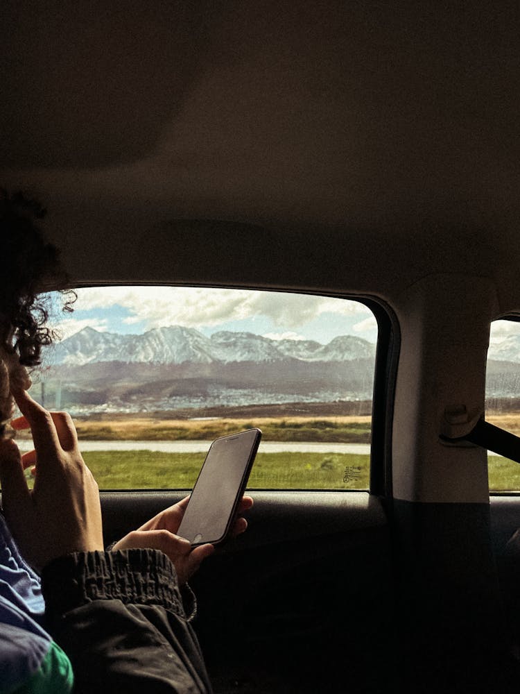 Man Sitting In The Backseat Of A Car And Using Phone 