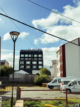 City view of modern buildings in Ushuaia, showcasing architectural styles under a blue sky.