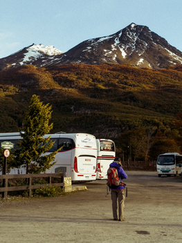 Backpacker stands in a parking lot in Ushuaia, Argentina, with snowcapped mountains in the background.