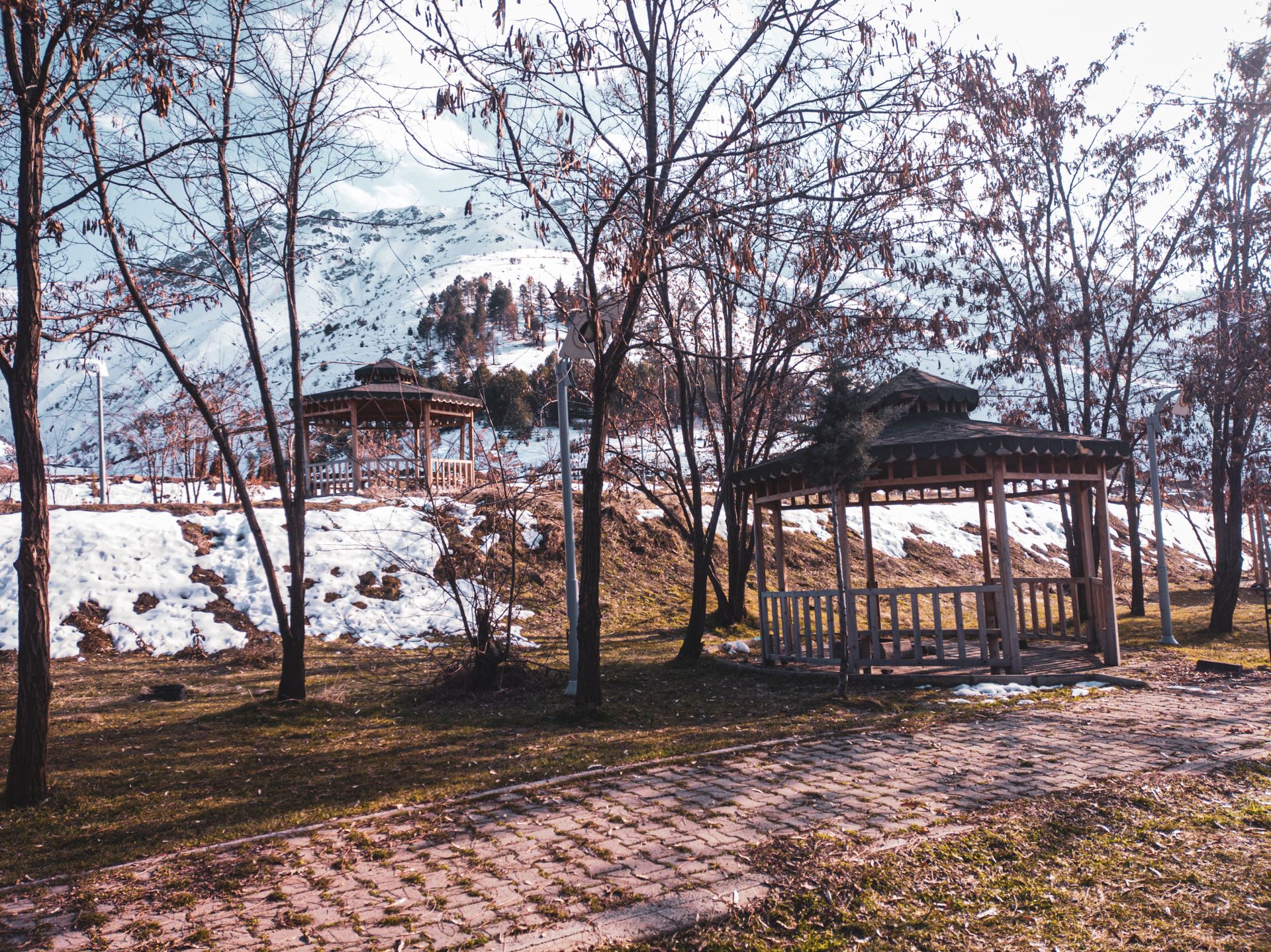 Pictorial winter landscape of gazebos amidst snowy mountains and trees in Sivrice, Türkiye.