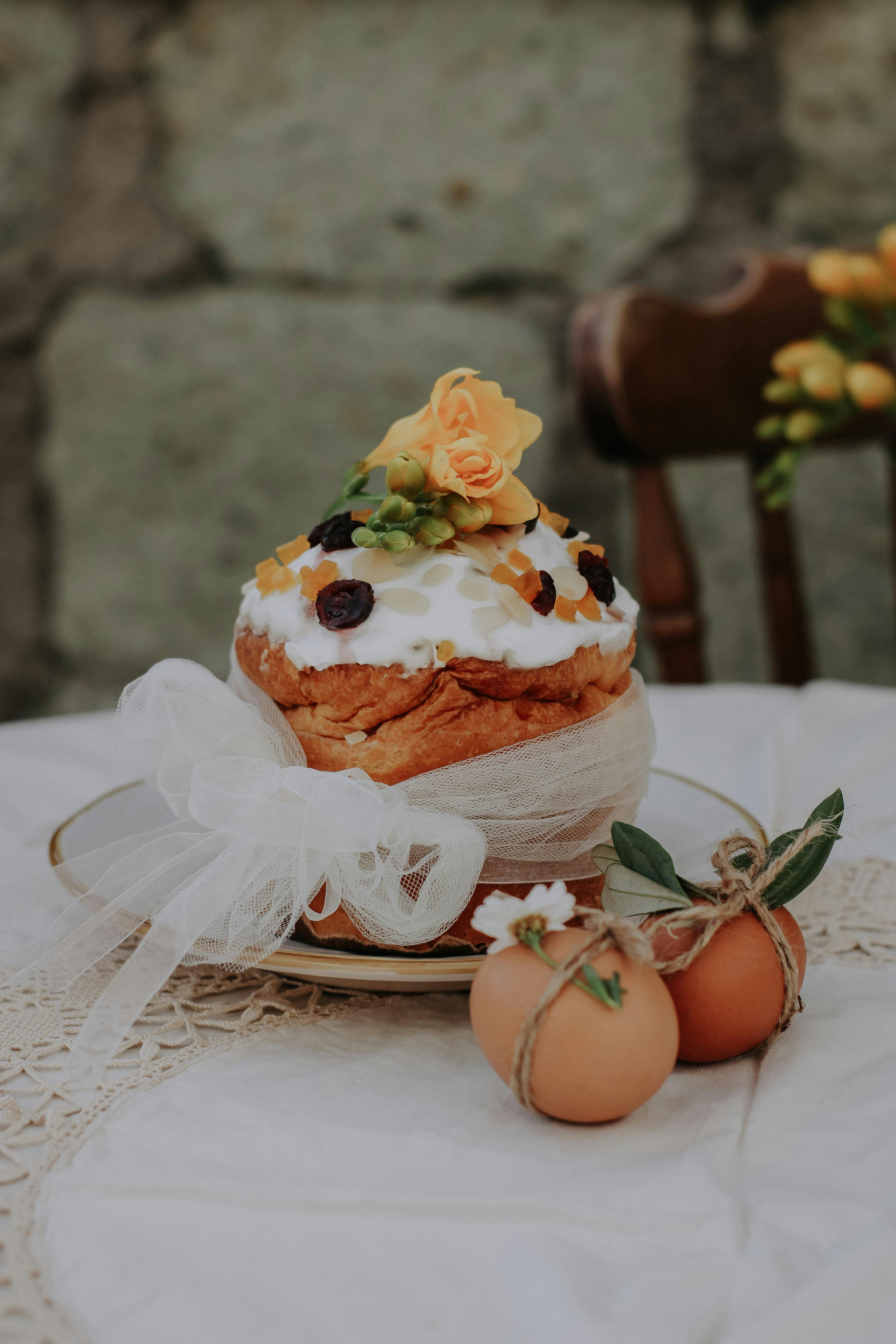 Easter cake decorated with fruits and flowers, adorned with eggs on a lace tablecloth.