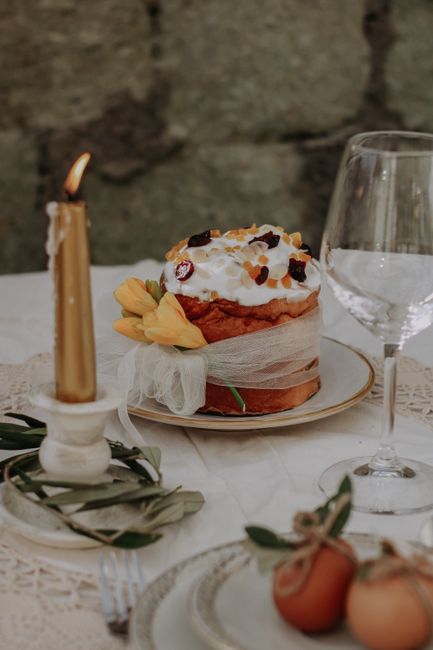 A beautifully decorated Easter cake with fruits and a candle on a rustic table setting.
