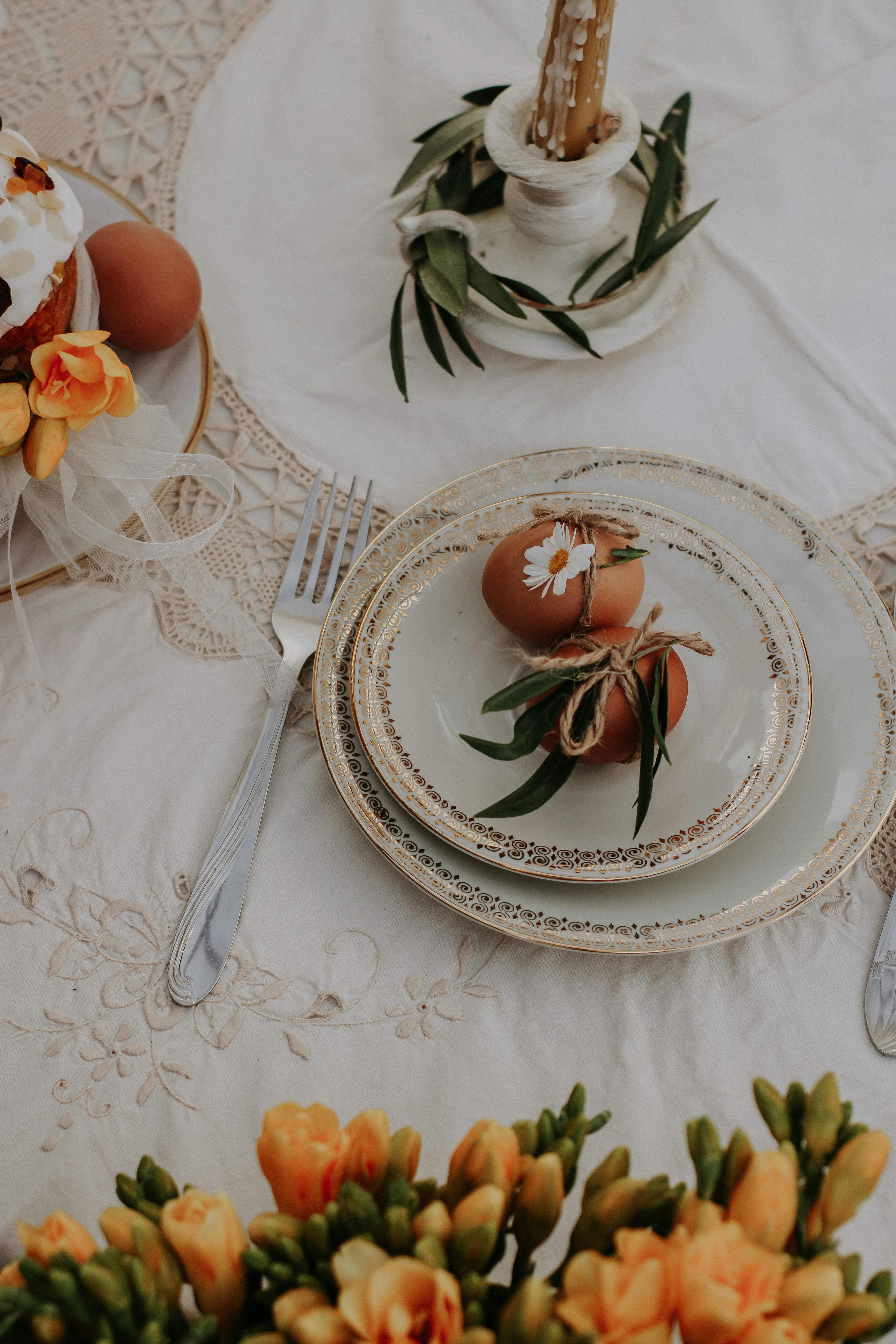 A beautifully arranged Easter table set with decorated eggs, flowers, and vintage cutlery.