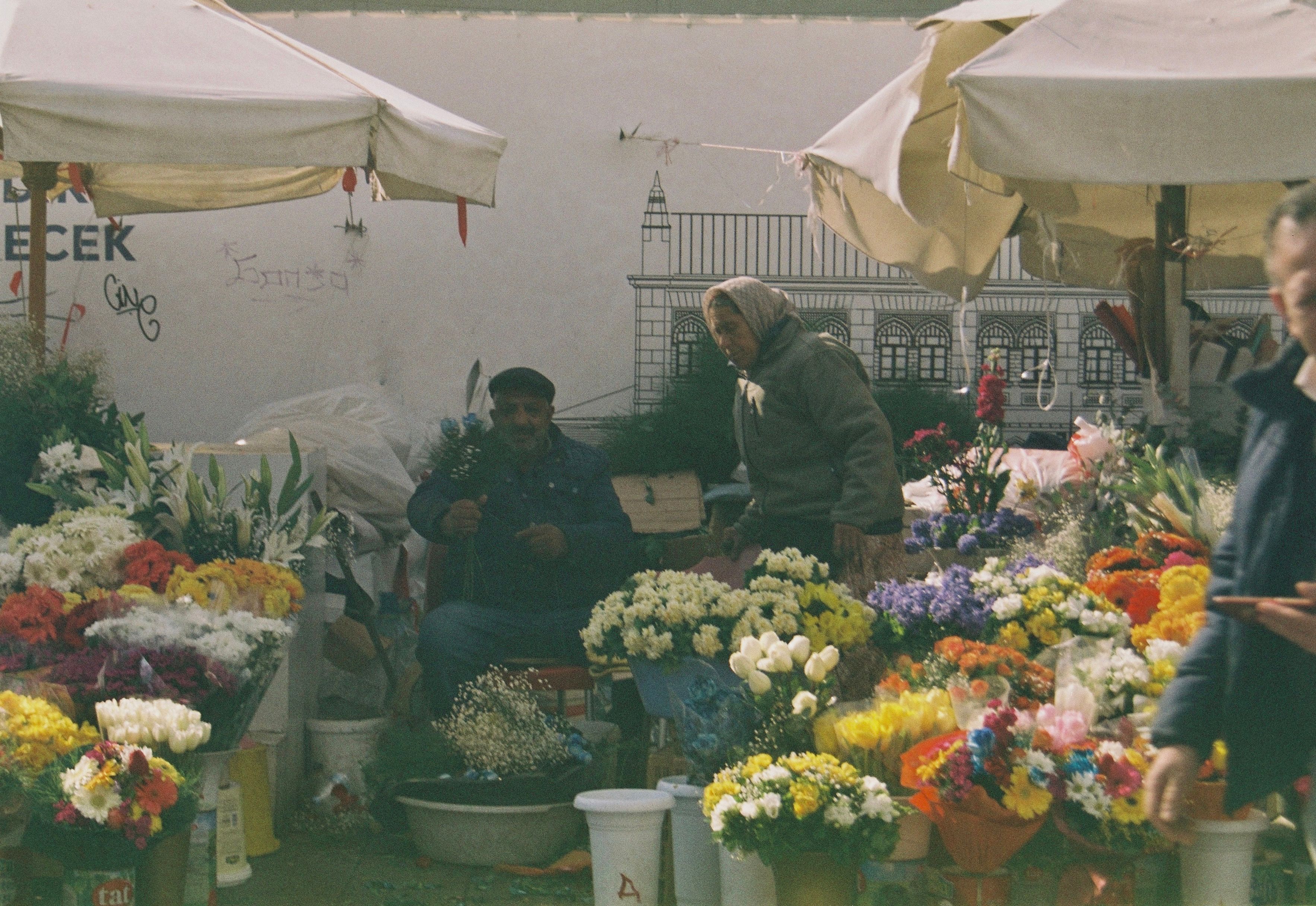 A man is standing in front of a flower stand · Free Stock Photo