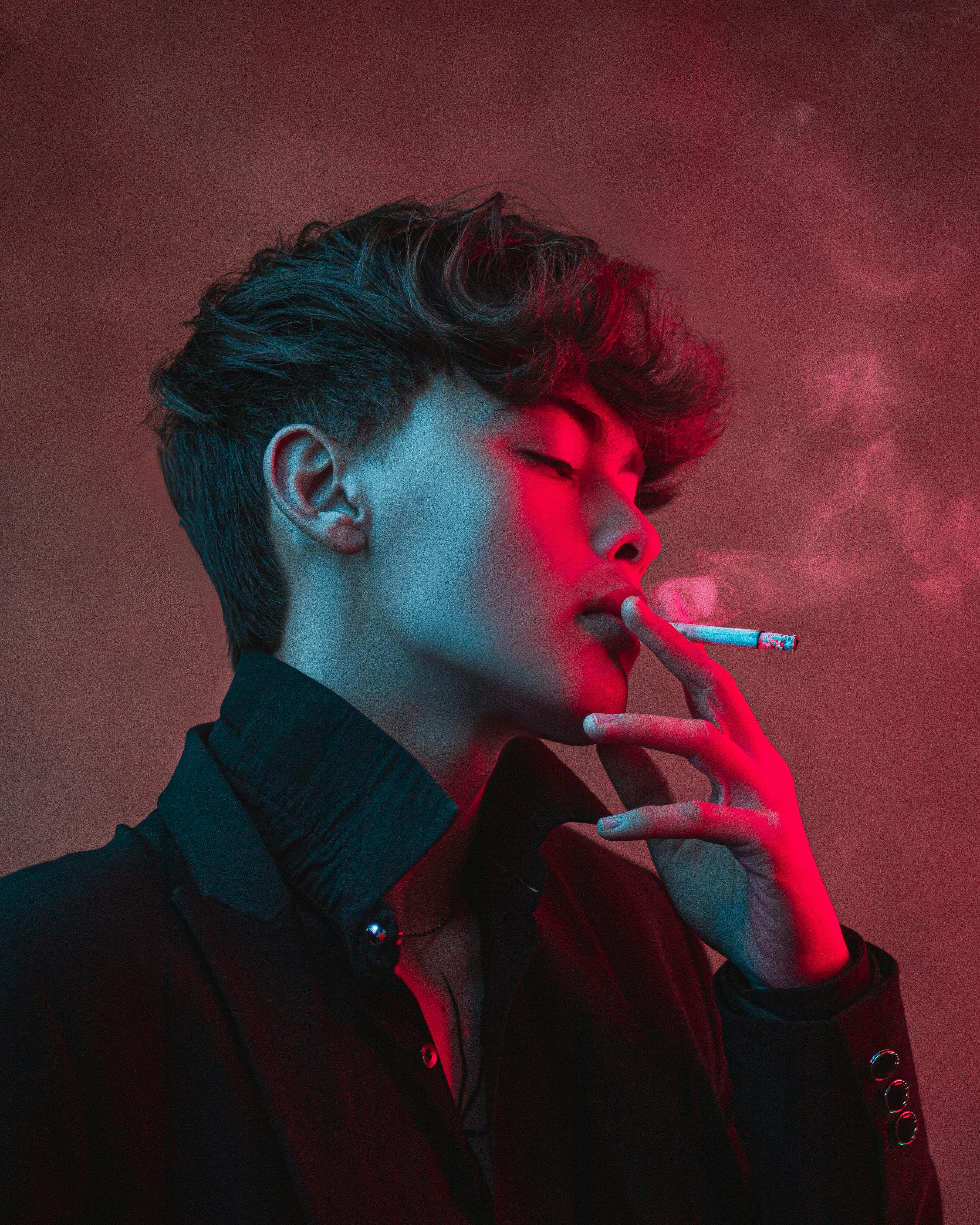 a man smoking a cigarette in a red light