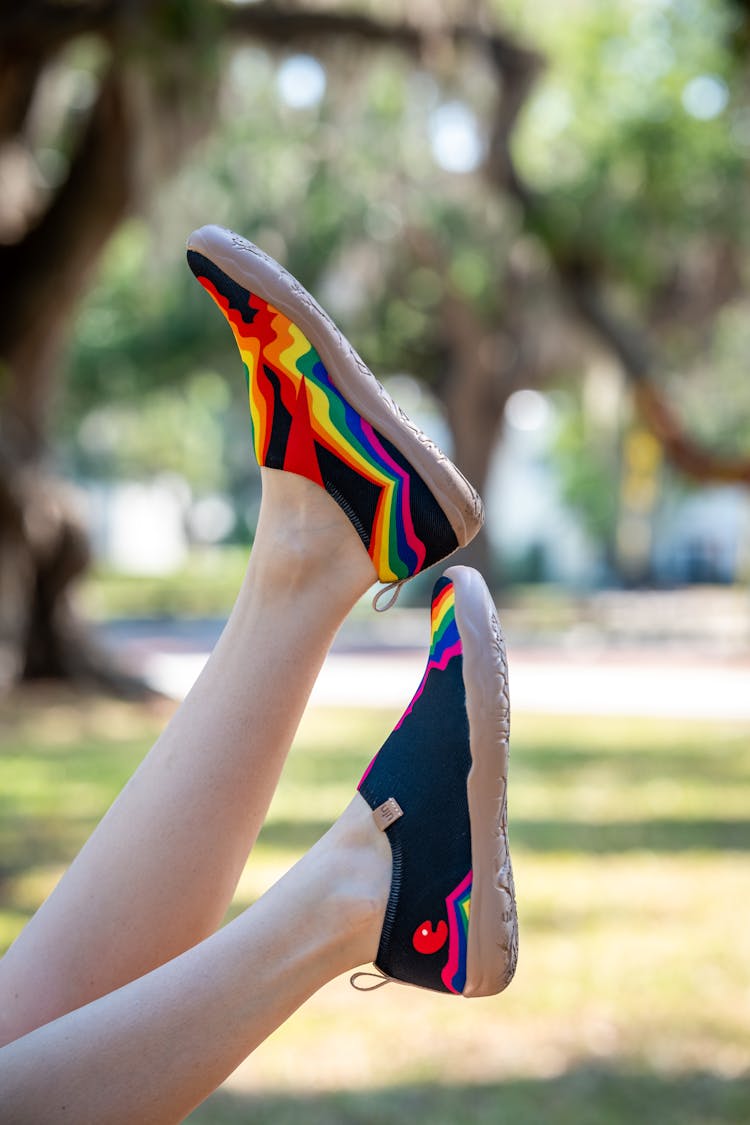 A Person's Feet Are In The Air With Colorful Shoes