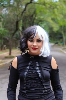 Woman in gothic fashion posing on a forest road, black and white wig, outdoors.