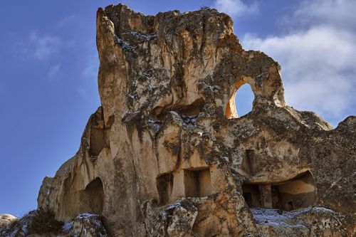 Free Impressive ancient rock formation with carved entrances under a blue sky, showcasing geological beauty. Stock Photo