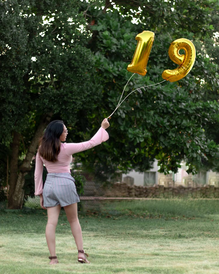 Young Woman Holding Balloons With Number 19 