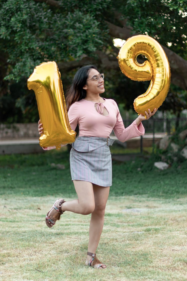 Young Woman Holding Balloons With Number 19 