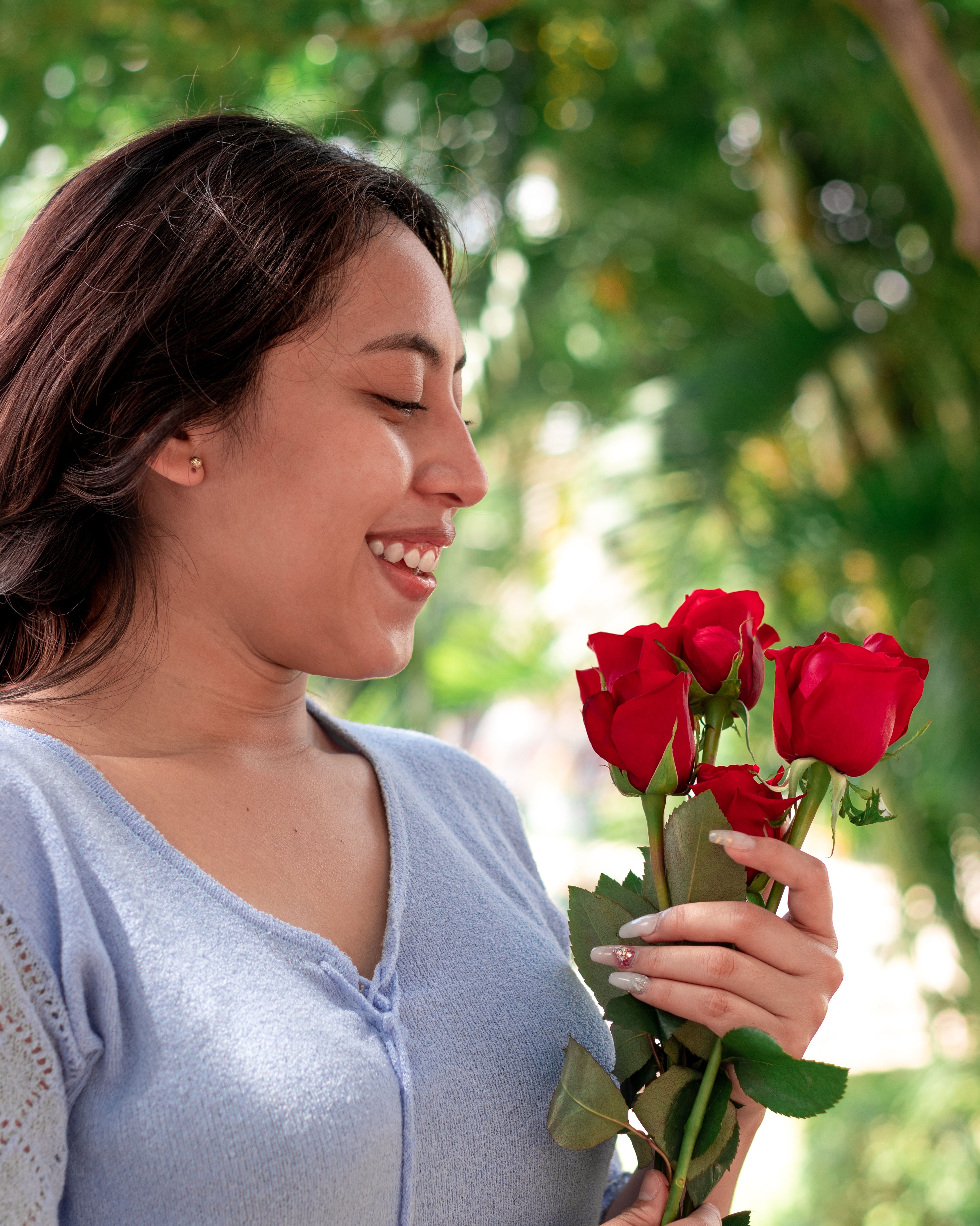 Woman Smiling Holding Red Roses Outdoors · Free Stock Photo