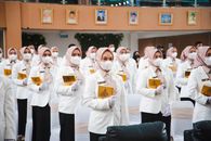 Muslim women in hijabs and masks during a graduation ceremony indoors.