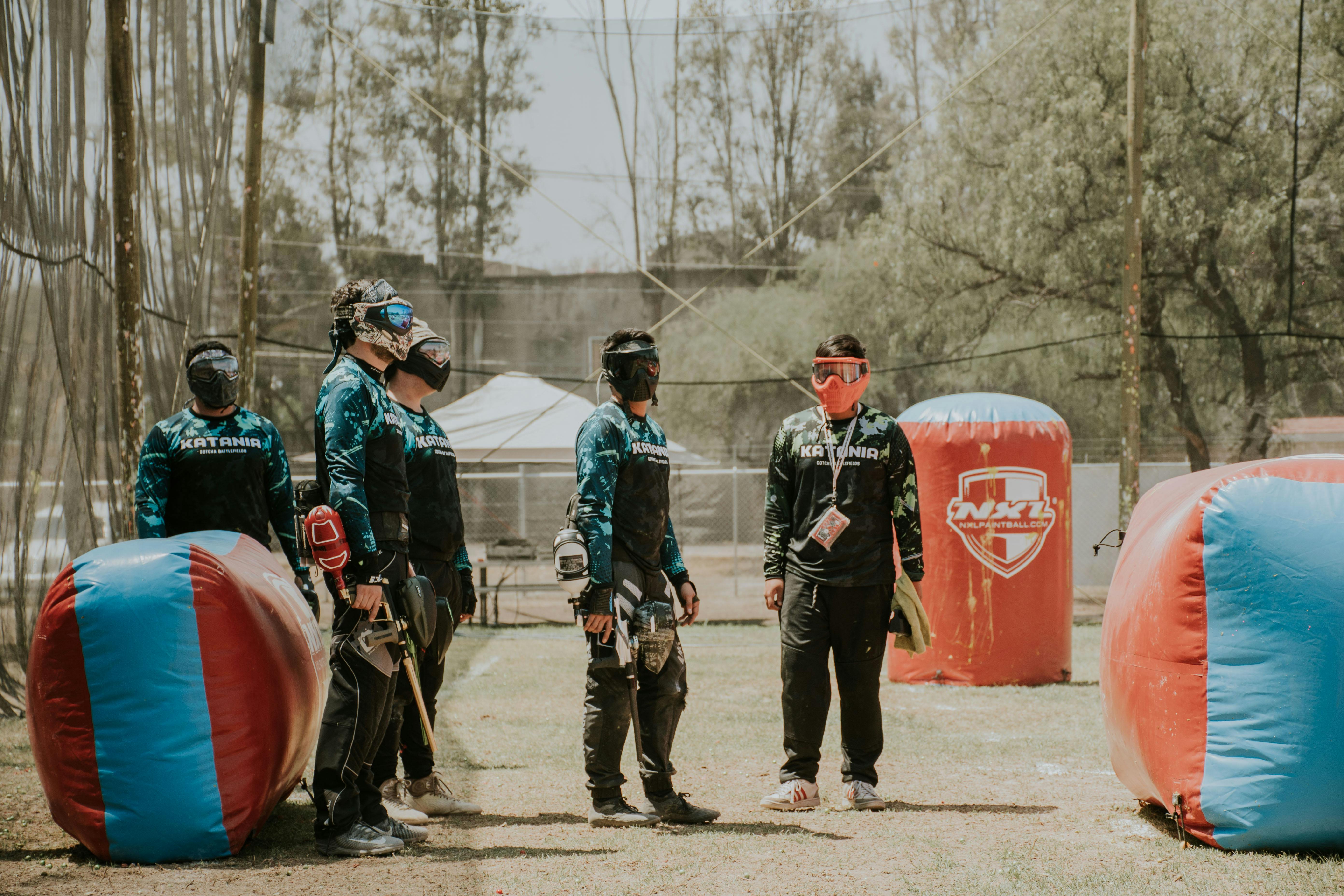 Group of men in paintball gear planning next moves in an outdoor field. Prescription Goggle Inserts - Group of men in paintball gear planning next moves in an outdoor field.