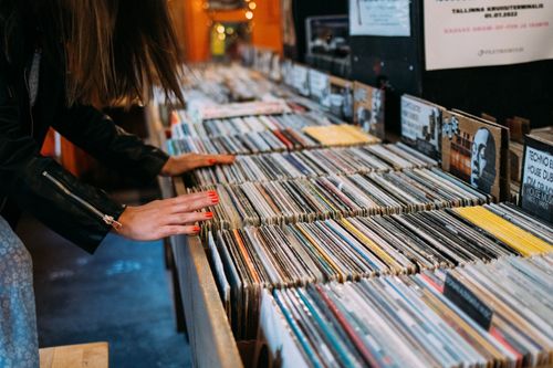 Free Woman browsing vinyl records in a cozy vintage music store, enjoying leisure time. Stock Photo