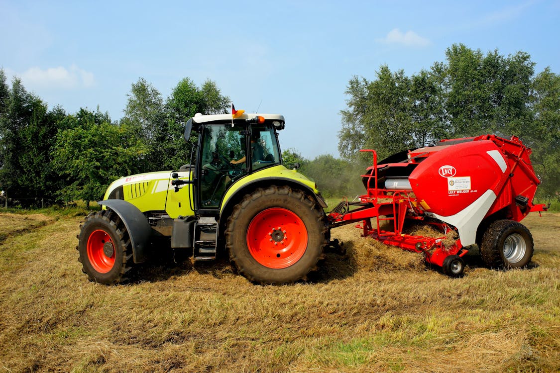 Bezpłatne Czerwony żółty I Biały Traktor Na Polu Trawy W Ciągu Dnia Zdjęcie z galerii
